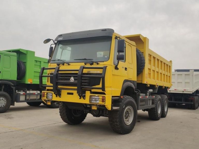 Yellow HOWO 6X6 dump truck parked in lot, showcasing its robust front grille and headlights with a protective grille.