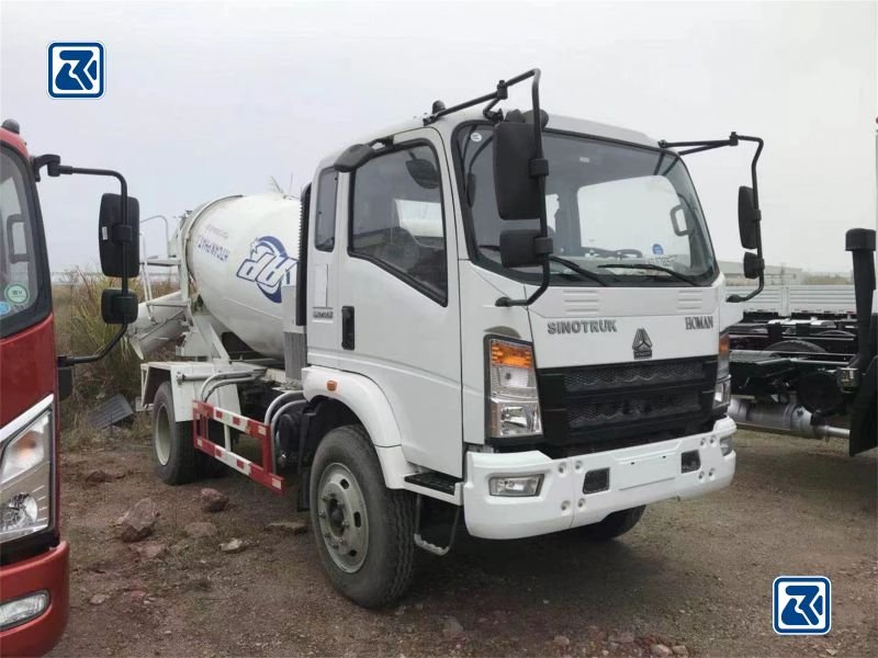 Side view of a white HOWO 4x2 concrete mixer truck parked on a gravel lot, displaying the driver's cabin and the cylindrical mixer drum with company branding.